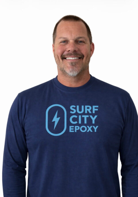 Sean Jensen, founder of Surf City Epoxy, wearing a navy company shirt with the Surf City Epoxy logo.